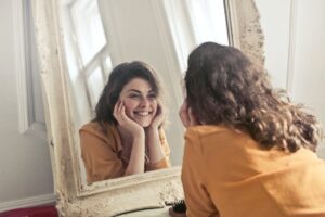 Une femme se regarde dans le miroir et souris